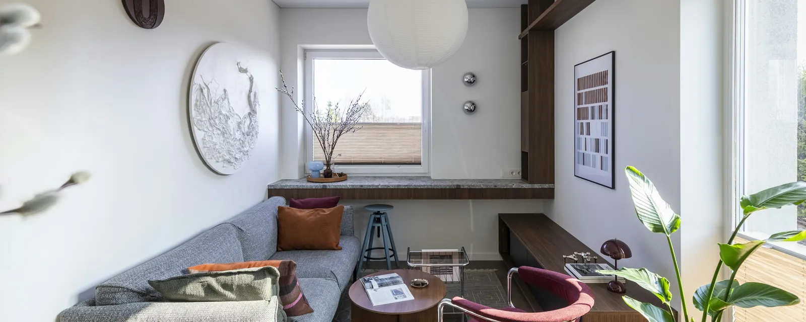 A bright modern living room with a grey sofa and large windows
